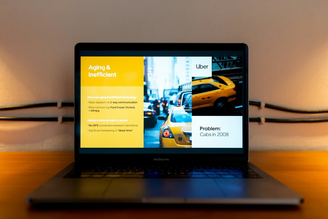 Silver MacBook Pro on wooden desk showing presentation on taxi technology.